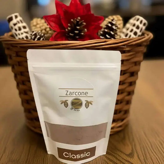 Zarcone Classic Cocoa package in front of a decorative basket with pine cones and a red flower.
